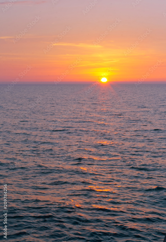 Fototapeta premium Sunset over the sea. Reflection of sunlight in the sea waves. Red sky in the rays of the sunset.