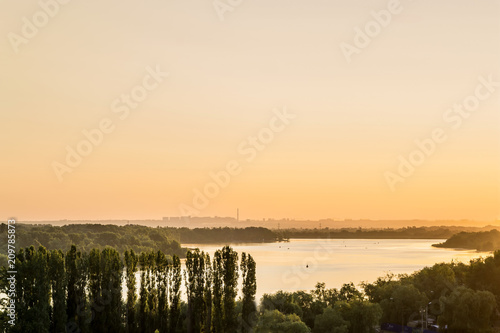 early morning on the river bank. view of the river with a small hill in the background city outlines