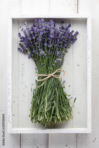 Beautiful lavender flowers bouquet in white wooden tray on planks, top view