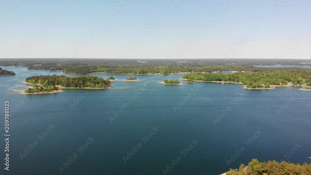 Panning drone shot over the Swedish archipelago near Stockholm. View of islands, forest and the coastline. Some boats passing by, heading for the Stockholm harbours. Panning drone shot over the Swedish archipelago near Stockholm. View of islands, forest and the coastline. Some boats passing by, heading for the Stockholm harbours.