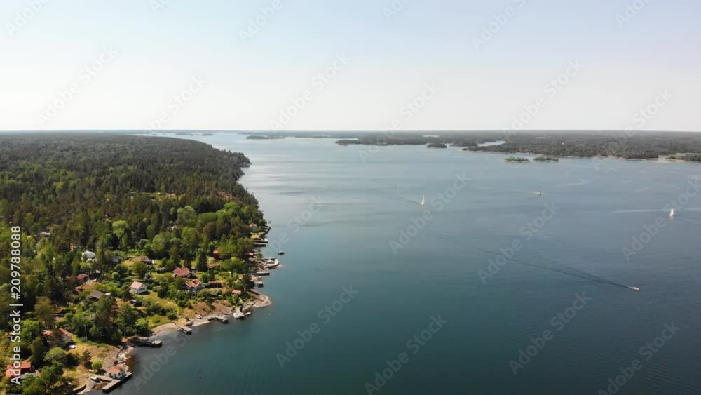 Panning drone shot over the Swedish archipelago near Stockholm. View of islands, forest and the coastline. Some boats passing by, heading for the Stockholm harbours. Panning drone shot over the Swedish archipelago near Stockholm. View of islands, forest and the coastline. Some boats passing by, heading for the Stockholm harbours.