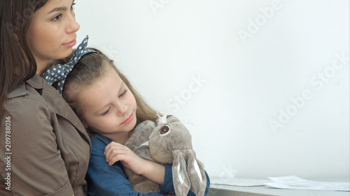 Young mother and her little daughter with bunny at the doctor