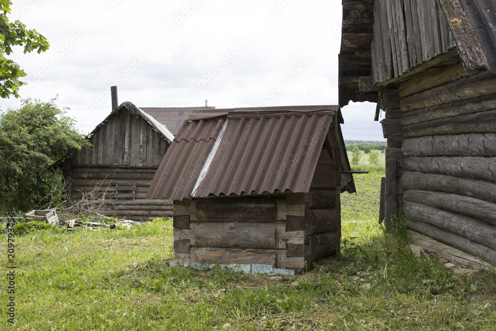 A small old wooden well at the wall of a village house A small old wooden well at the wall of a village house