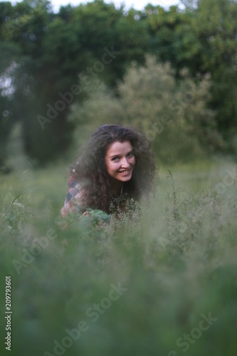 Young, beautiful woman on nature. Young woman with dark curly hair.