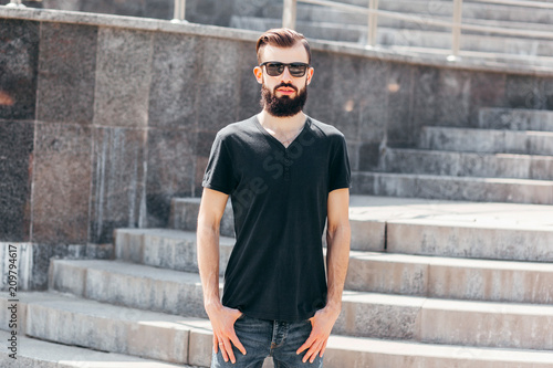 Stylish man male model with beard wearing black blank t-shirt with space for your logo or design in casual urban style