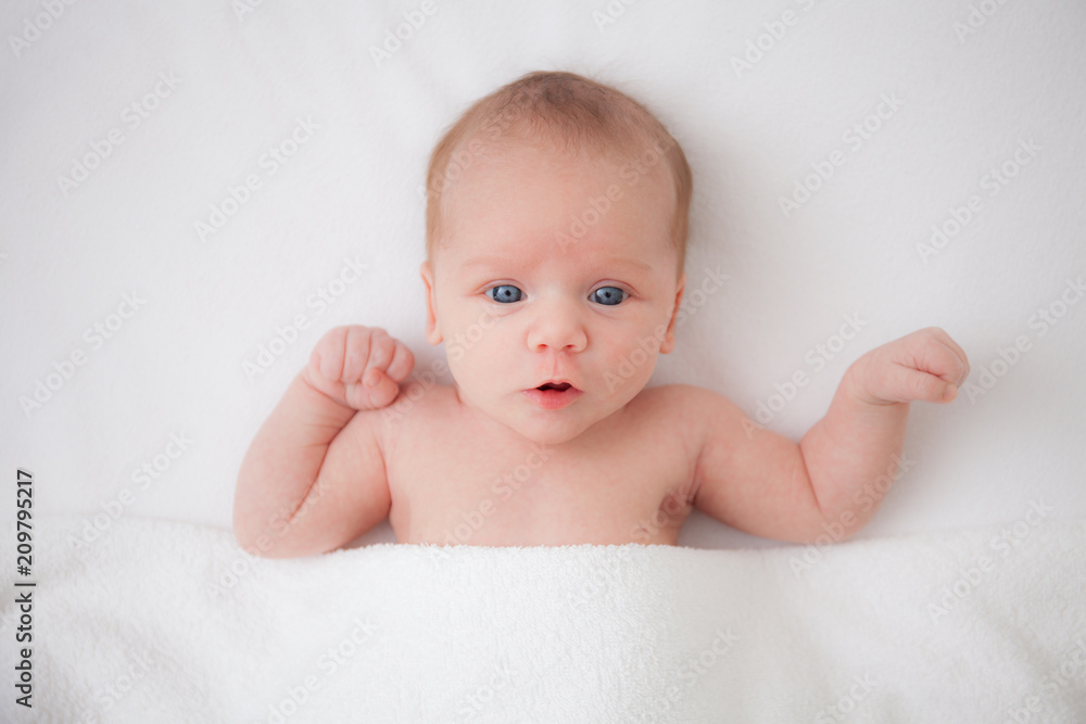 Cute adorable newborn baby girl in white bed and looking at the camera Cute adorable newborn baby girl in white bed and looking at the camera