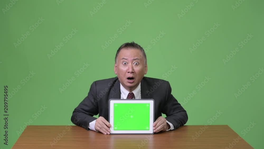 Mature Japanese businessman showing digital tablet Mature Japanese businessman showing digital tablet