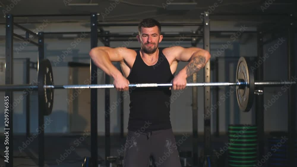 Strong bearded tattooed man at a crossfit gym lifting a barbell. Strong bearded tattooed man at a crossfit gym lifting a barbell.