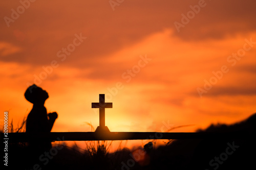 Boy praying to God with cross, christian silhouette concept.