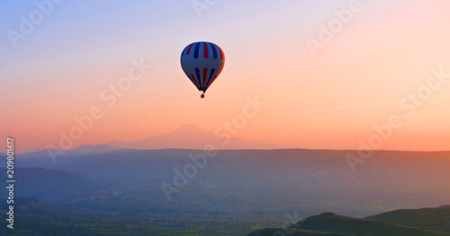 Hot air balloon flying over amazing landscape at sunrise, Cappadocia, Turkey © olenatur
