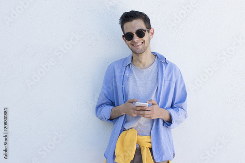 young man with mobile phone to fashion on the blue wall