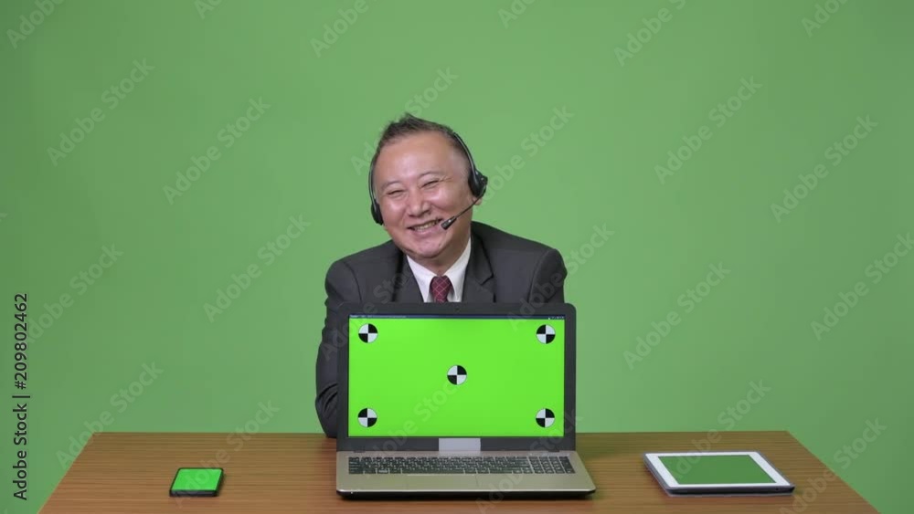 Mature Japanese businessman working as call center representative Mature Japanese businessman working as call center representative
