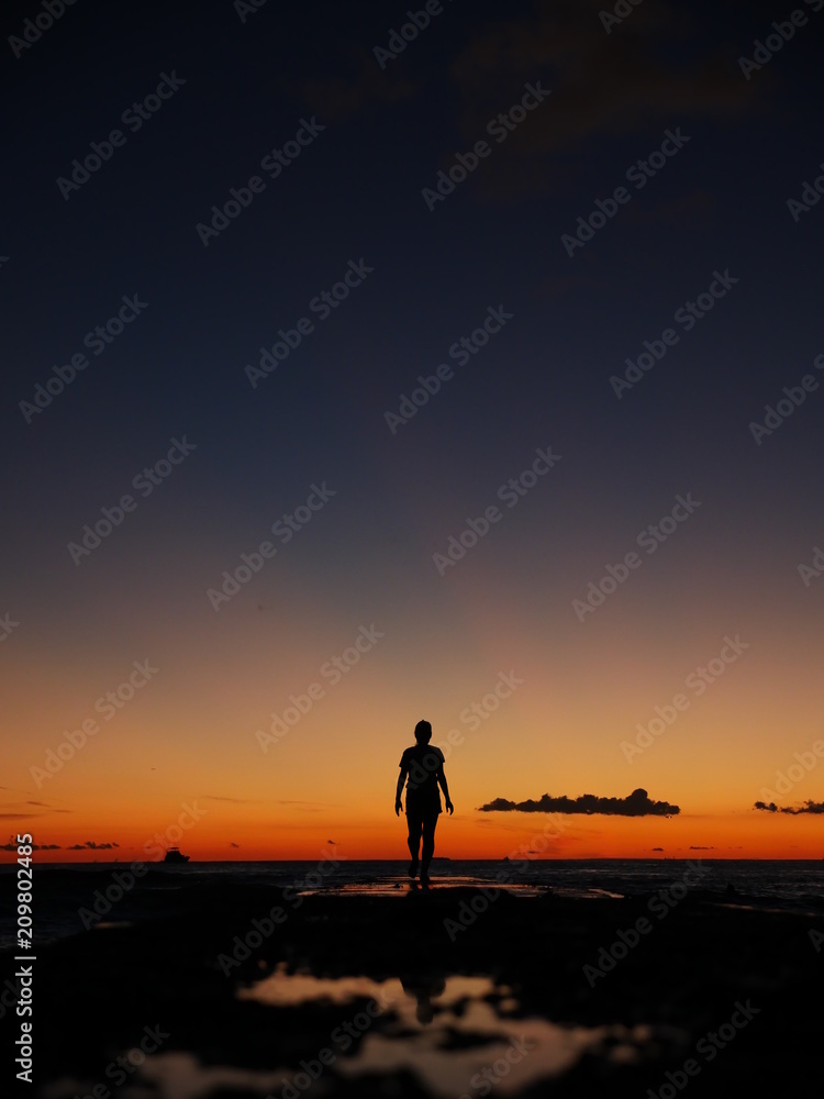 woman silhouette walking on pier into a colorful sunset