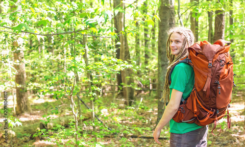 Happy male hiker with backpack trekking through the forest