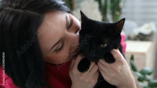 love for pets. beautiful dark-haired girl with a black cat is relaxing at home in the bed room