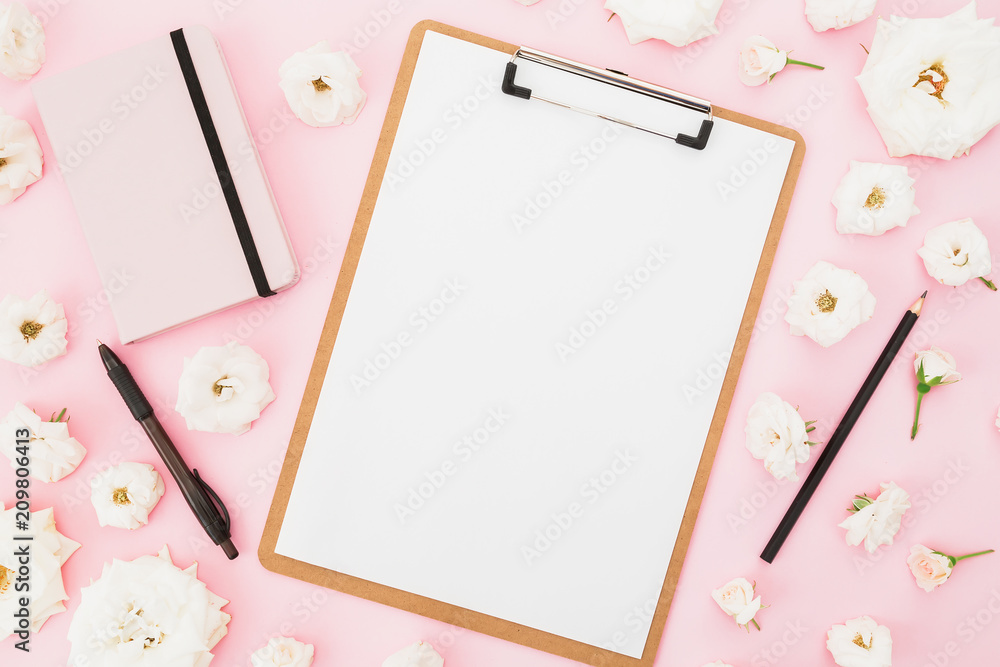 Roses flowers with clipboard, notebook and black pen on pink background. Flat lay, top view. Freelancer business concept. Roses flowers with clipboard, notebook and black pen on pink background. Flat lay, top view. Freelancer business concept.
