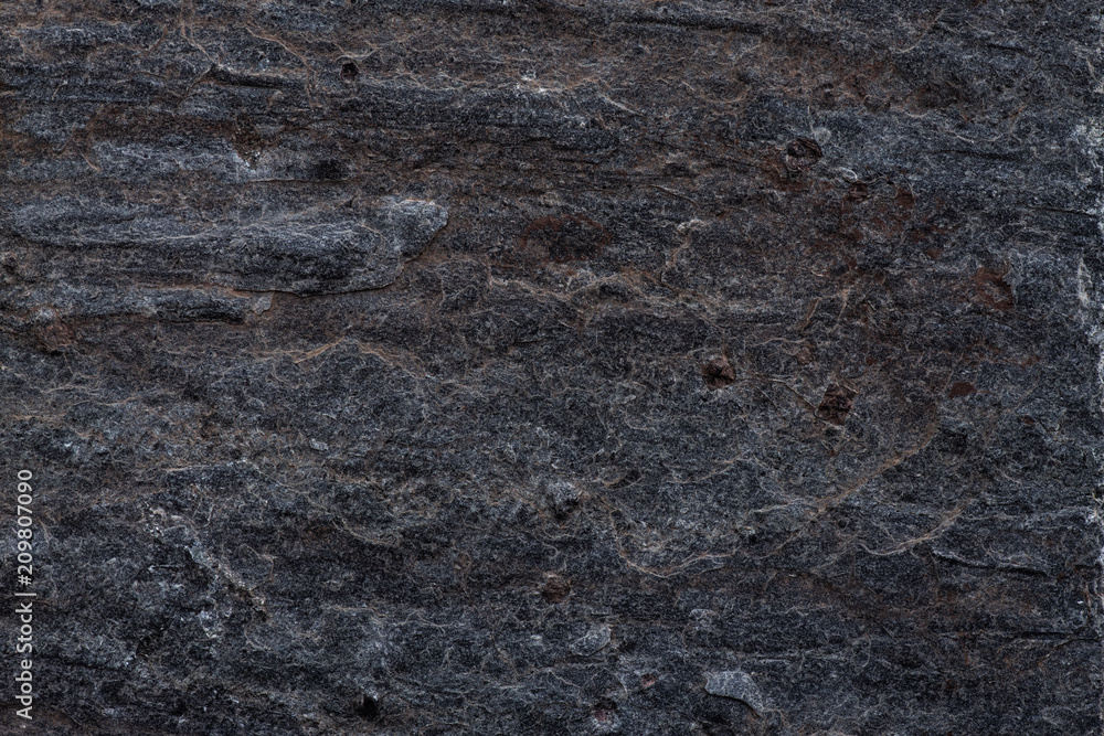 Close-up of a dark rock surface featuring natural striations and rugged texture, ideal for backgrounds, industrial designs, and architecture content. Close-up of a dark rock surface featuring natural striations and rugged texture, ideal for backgrounds, industrial designs, and architecture content.