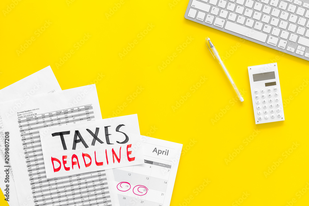Taxes deadline words on office work desk with calendar and bills on yellow background top view copy space. Circled dates Taxes deadline words on office work desk with calendar and bills on yellow background top view copy space. Circled dates