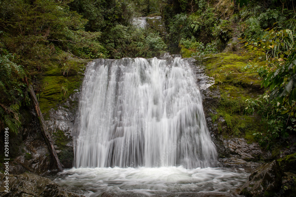 Obraz premium Waterfall in a forest with mossy rocks