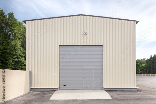 facade of industrial storehouse with closed gray metal gate and door