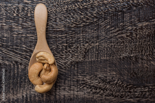 Raw cashew nuts in bowl on textured wooden background, table top view