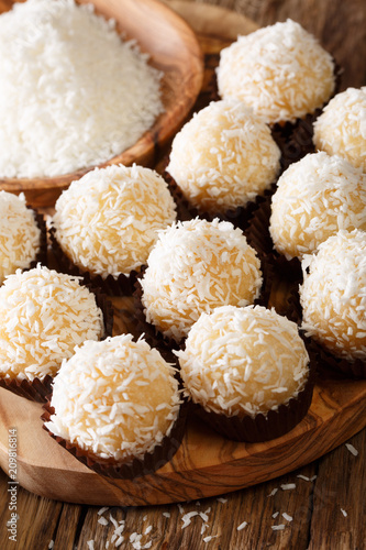 Brazilian Coconut Kisses (Beijinhos de Coco) condensed milk and coconut flakes close-up. Vertical photo