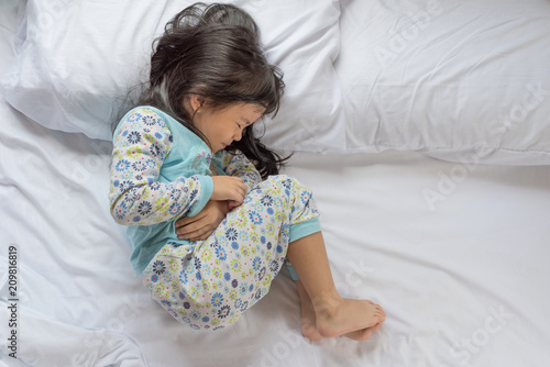 a little girl in her bed has a stomachache