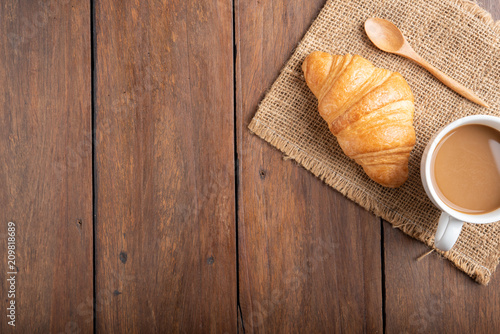 Coffee and croissant on wooden background