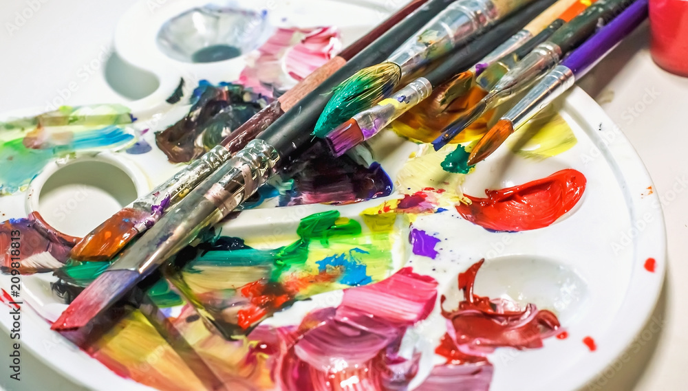 Art brushes and paints for painting on the used palette with paints close-up. Art brushes and paints for painting on the used palette with paints close-up.