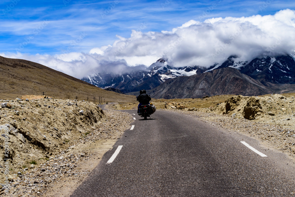 Fototapeta premium Biker Going To Explore Gurudongmar Lake With Snow Covered Mountain In The Horizon
