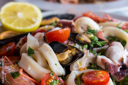 Fresh mediterranean seafood. Calamari, octopus, mussels and shrimps with tomatoes and lemon. Delicious seafood salad. Italian tasty cuisine. 