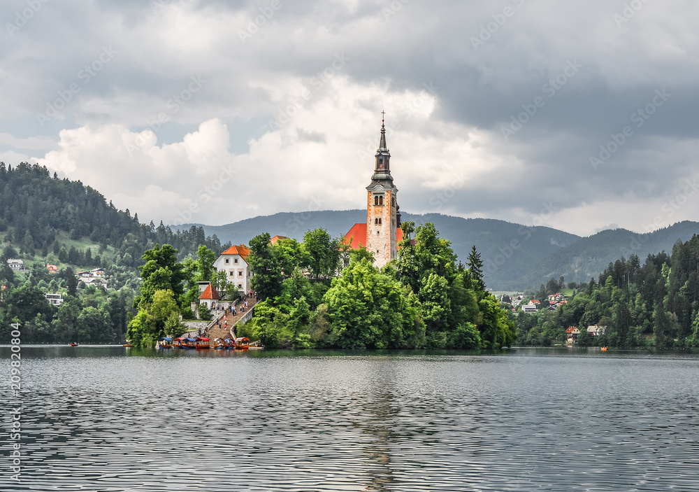 Bled, Slovenia - May 20, 2018: Beautiful Lake Bled in the Julian Alps and Assumption of Mary Church, Bled Slovenia. Mountains, Old church in the middle of the lake and dramatic sky. Bled, Slovenia - May 20, 2018: Beautiful Lake Bled in the Julian Alps and Assumption of Mary Church, Bled Slovenia. Mountains, Old church in the middle of the lake and dramatic sky.