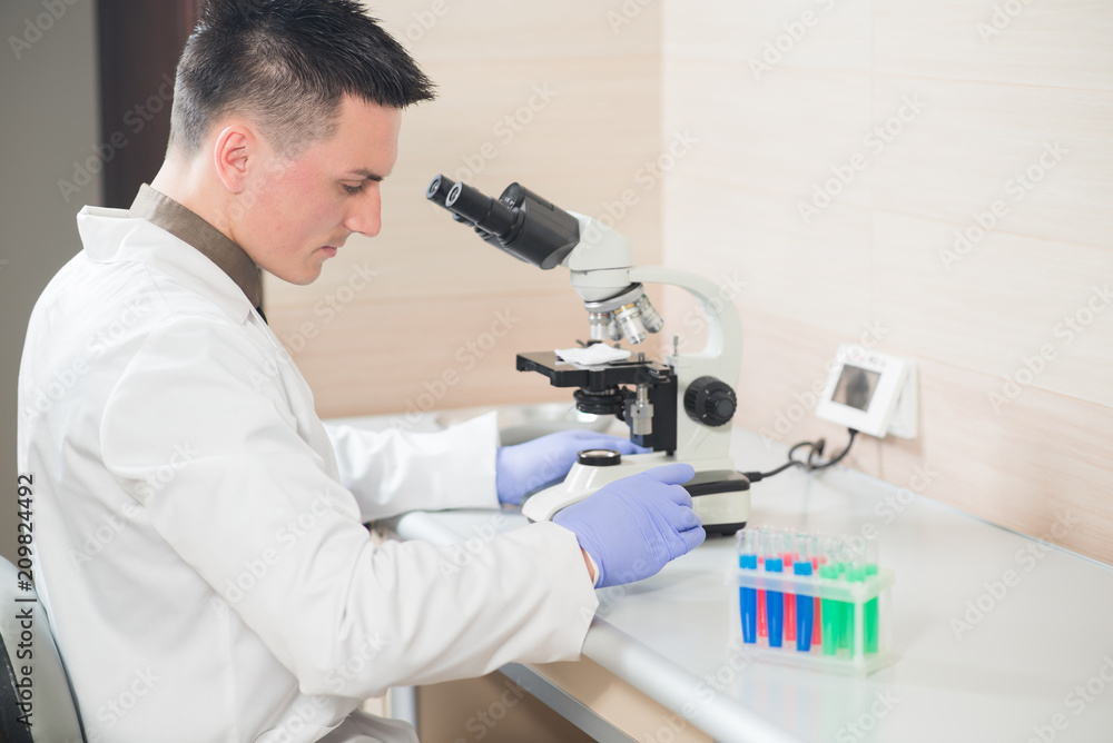 A young man scientist or doctor working with test tubes in lab