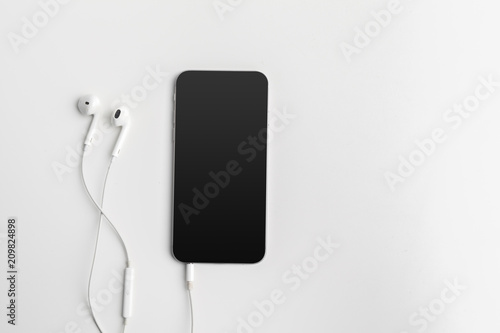 Creative flat lay photo of workspace desk with earphones and mobile phone