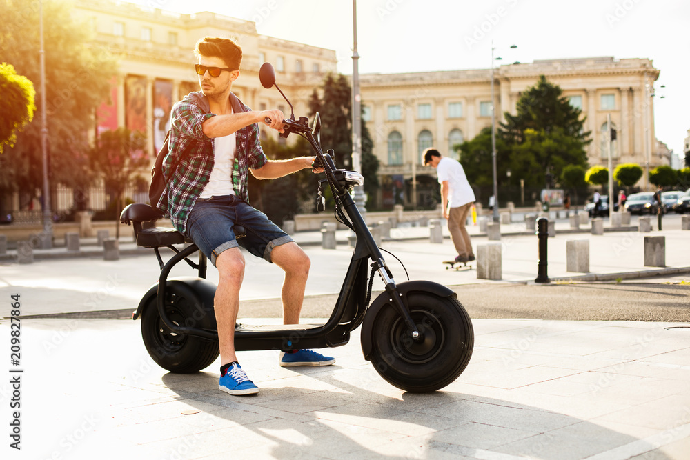 Fototapeta premium młody mężczyzna siedzi na pojeździe elektrycznym