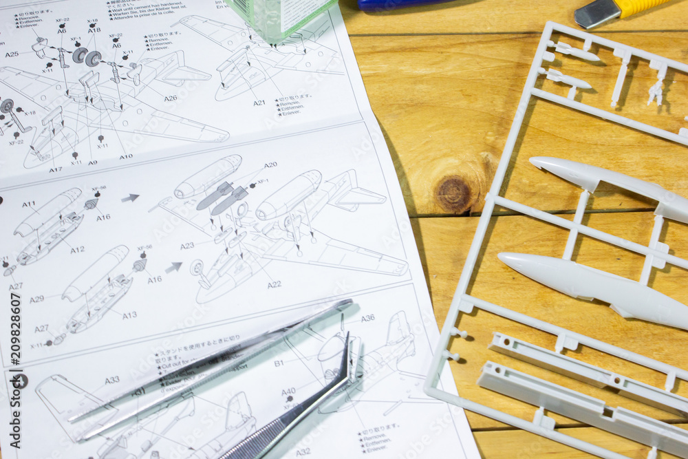 Fototapeta premium Plastic model part WW2 airplane and tools on wooden workbench closeup.