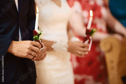 happy bride and stylish groom holding candles wedding ceremony, wedding couple at matrimony in church, emotional moment, religion unity concept photo