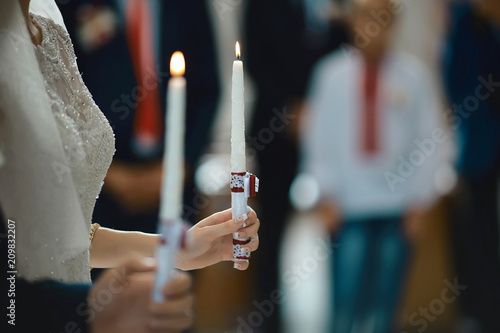 happy bride and stylish groom holding candles wedding ceremony, wedding couple at matrimony in church, emotional moment, religion unity concept