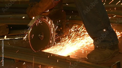 worker cutting metal angle bar by grinder machine with sparks photo
