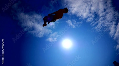 Wallpaper Mural Young guy dark silhouette jumping on the trampoline on sky sun background slow motion sport activity Torontodigital.ca