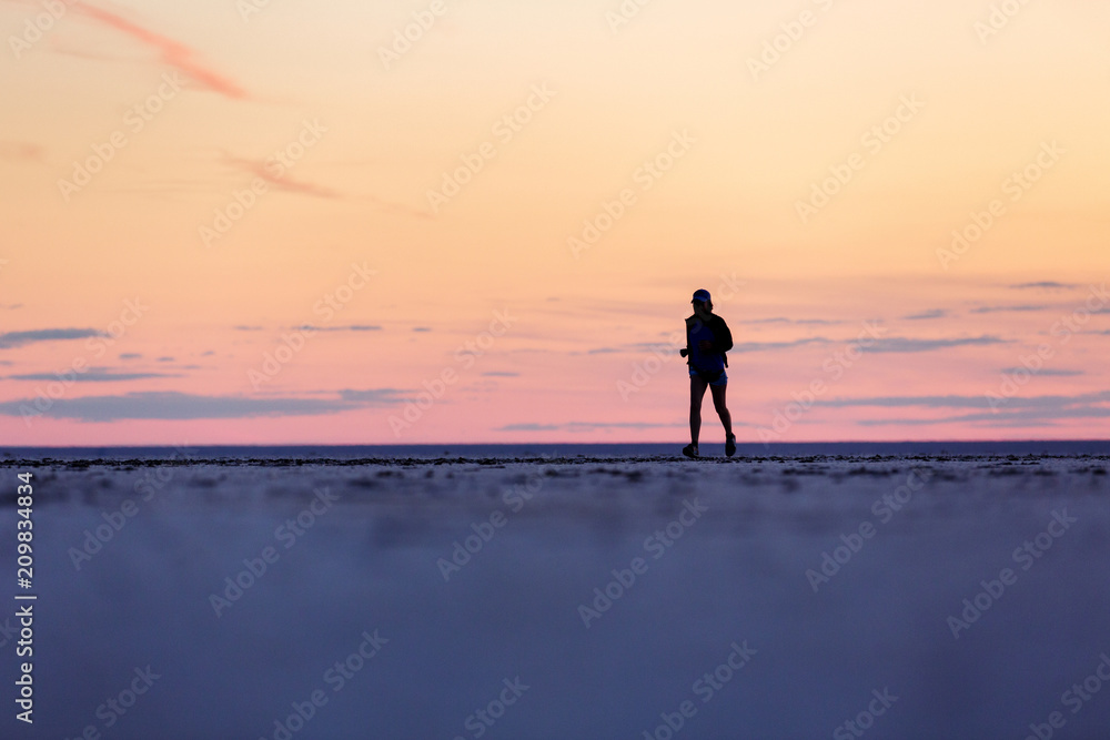 Silhouetted girl against the beautiful sky. Sports training on the beach.
