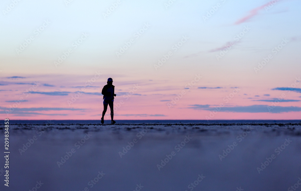 Silhouetted girl against the beautiful sky. Sports training on the beach.
