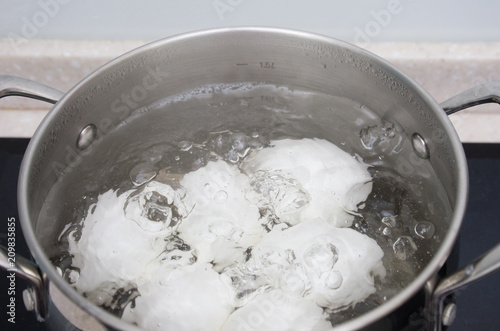 White chicken eggs boil in a saucepan