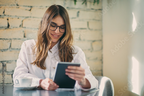 Young modern woman sitting in cafe and using tablet.