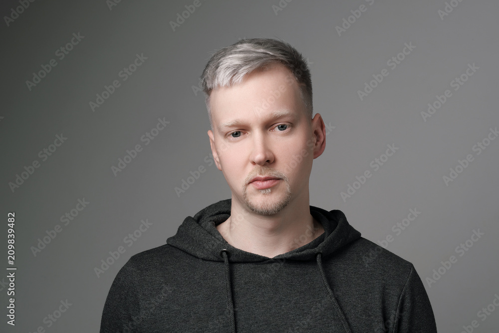 Young man with gray hair in casual clothes on white and gray background. Portrait in the studio. Creative hair coloring. Young man with gray hair in casual clothes on white and gray background. Portrait in the studio. Creative hair coloring.