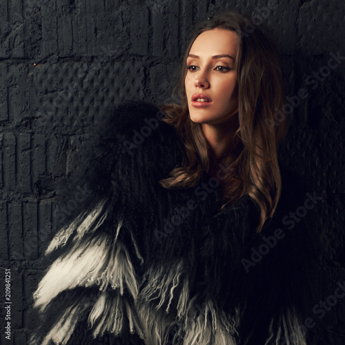 Photography Magnificent caucasian brunette woman wearing trendy faux fur coat with long black and white hair and thigh high boots
