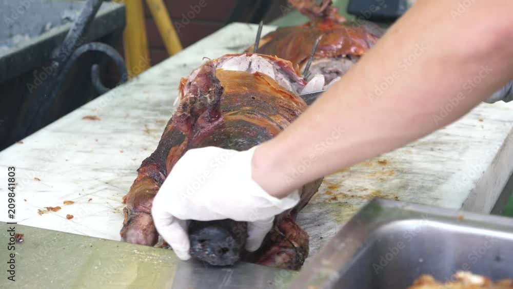 Cutting slicing just roasted on spit pig meat on street food festival in Sofia Bulgaria Cutting slicing just roasted on spit pig meat on street food festival in Sofia Bulgaria