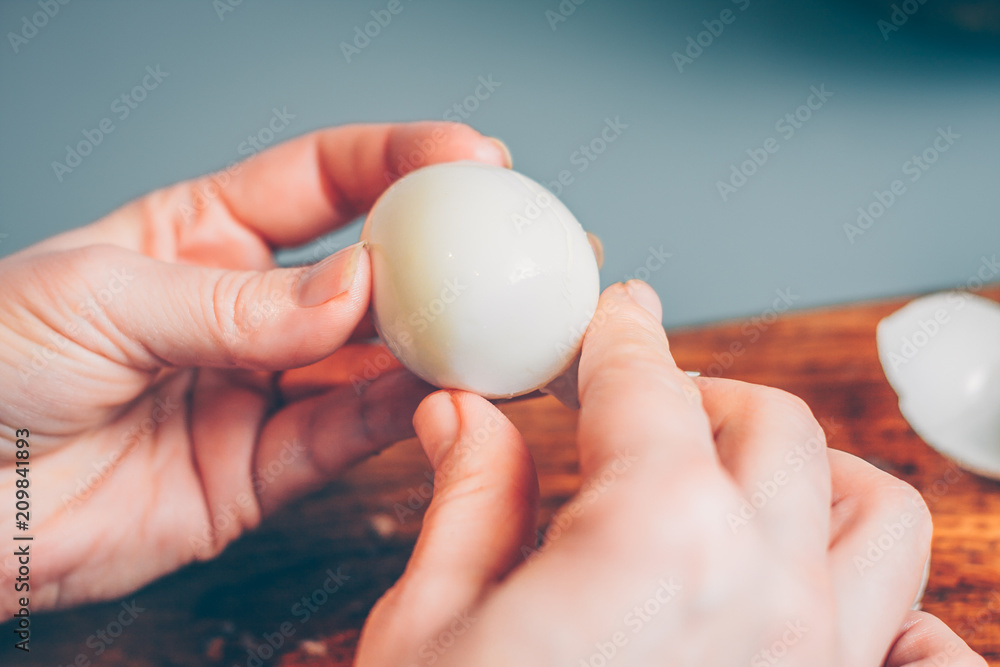 A woman cleans a boiled egg from the shell, a first-person view A woman cleans a boiled egg from the shell, a first-person view