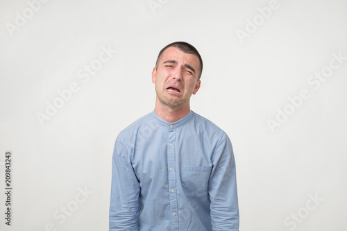 Studio shot of young handsome man, pouting and crying, complaining about girlfriend.