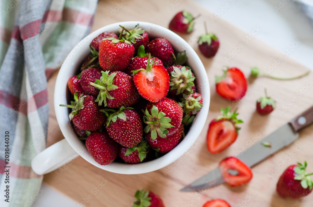 Red strawberries in the white cup on the table